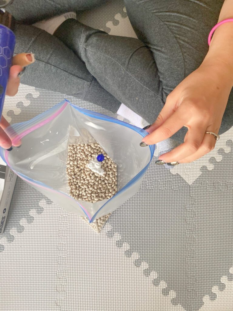 dyeing sensory filler using paint and hand sanitizer. In this step, you are mixing the ingredients in a ziploc.