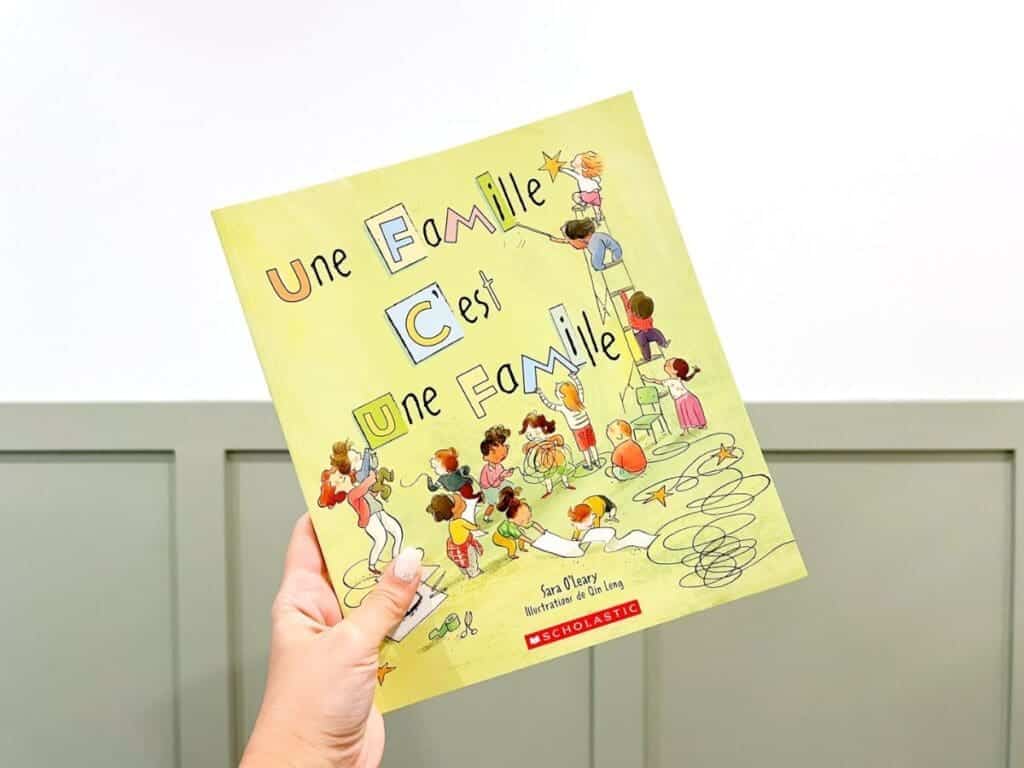 A hand holding French books about families