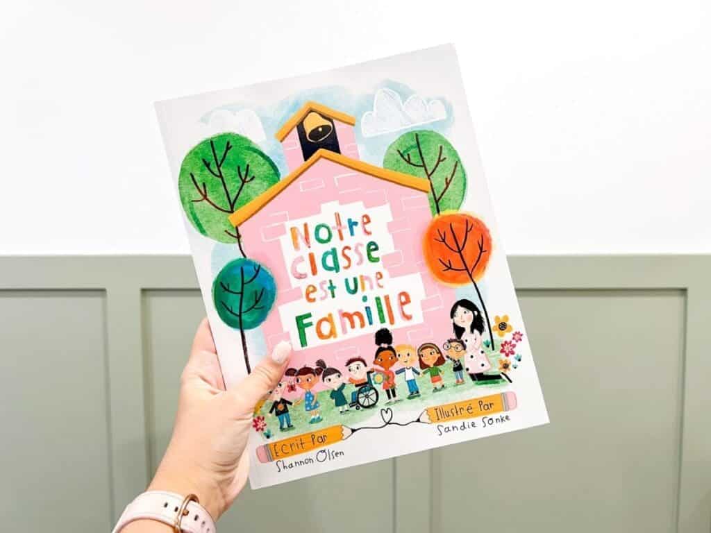 A hand holding French books about families