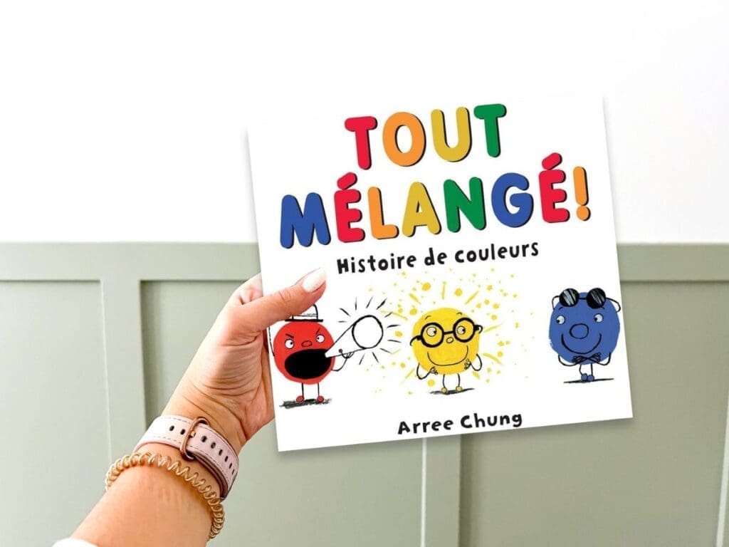 A hand holding a French picture book about blending families